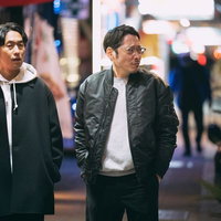 夜の繁華街の路地を歩く調査中の男性の探偵シーンの写真