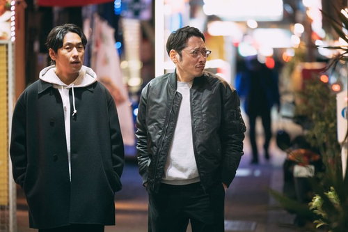 夜の繁華街の路地を歩く調査中の男性の探偵シーン