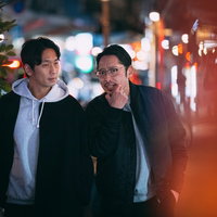 夜の繁華街で調査にあたる探偵のふたり、ネオン商店街を歩くの写真