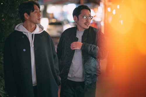 夜の商店街を調査する探偵のふたり、ネオン看板の飲み屋街を歩く