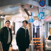 繁華街の夜間に周囲を確認する調査中の男性ふたりの写真