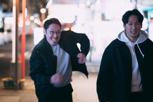 夜の街を走って追跡する眼鏡をかけた男性の全力ダッシュ