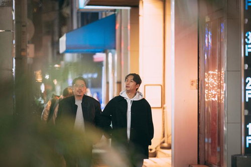 夜の街を散歩しながら会話を楽しむ二人の男性