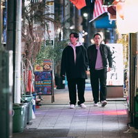 夜の繁華街を歩く探偵の二人組 ネオン商店街での調査の写真