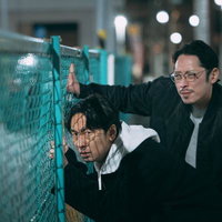 夜間のフェンス越しに尾行する探偵の二人が監視対象を追跡の写真