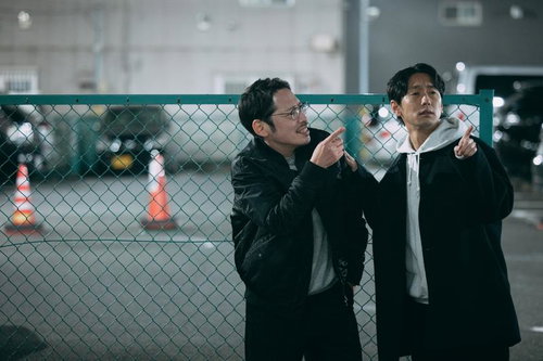 夜の駐車場で指差し確認する二人の探偵