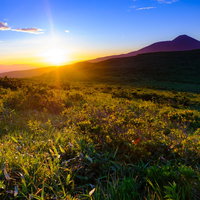 夕陽が沈む霧ヶ峰高原の草原と稜線の夕焼け風景の写真