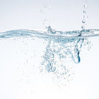 ポチャンと水槽に水が滴る瞬間。透明な水中での水滴落下の写真