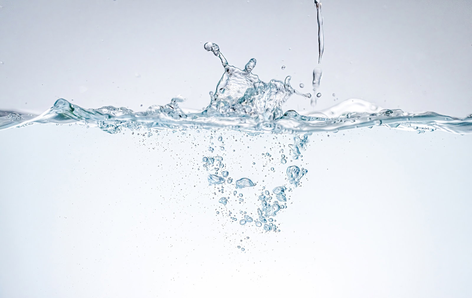 透明な水が水面に落ちて波紋と気泡を作る瞬間