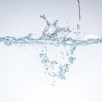 水面に水が落ちて波紋と気泡が生まれる瞬間の写真