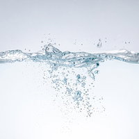 水が注がれて水槽に飛び散る気泡とミネラルウォーターの写真