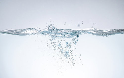 水が注がれて水槽に飛び散る気泡とミネラルウォーター