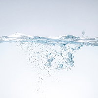 ミネラルウォーターに浮かぶ無数の気泡と水滴の写真