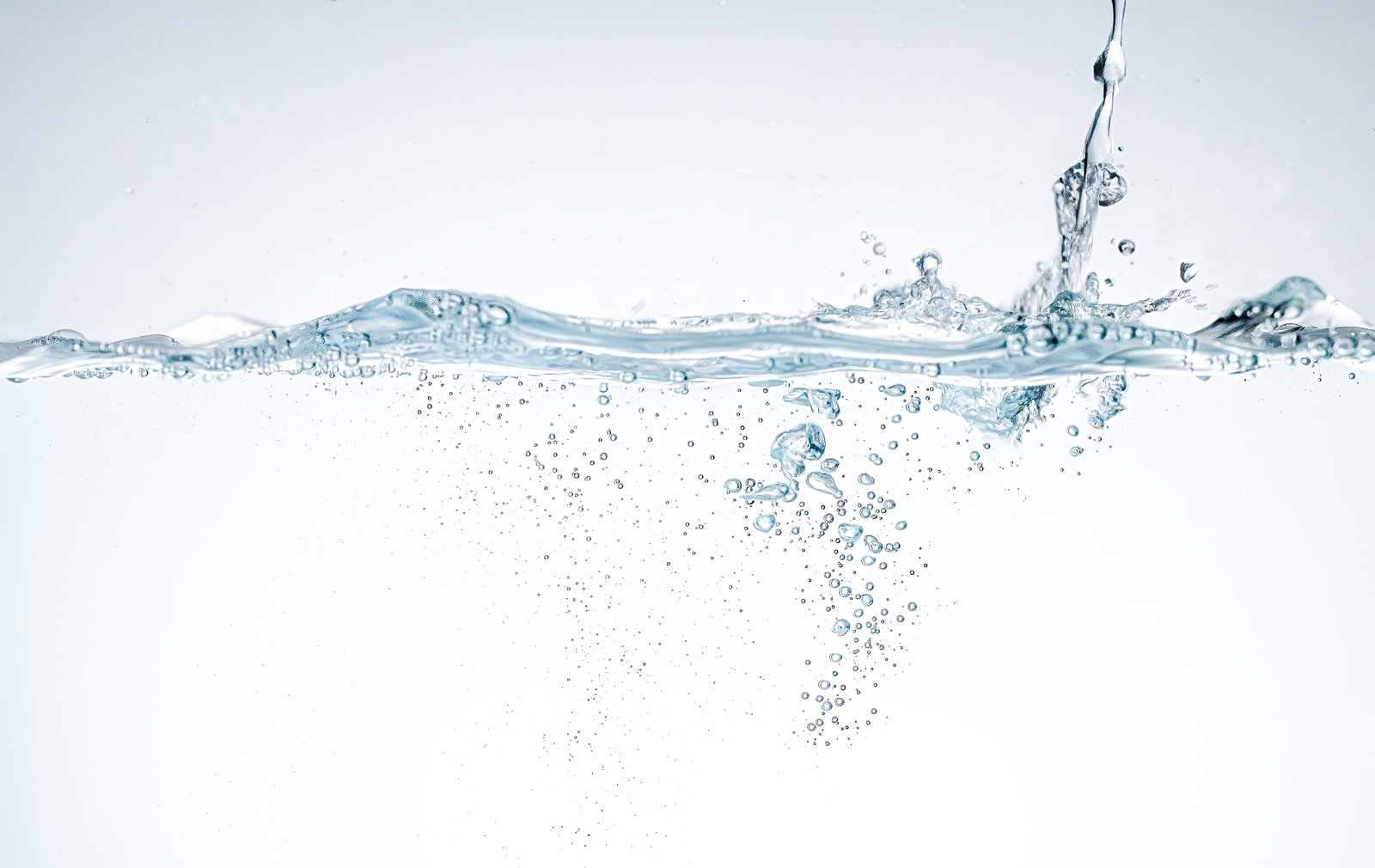 水面に注がれる透明な水と立ち上がる気泡の瞬間
