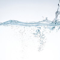 水槽の水面に注がれる透明な水の流れと気泡の写真