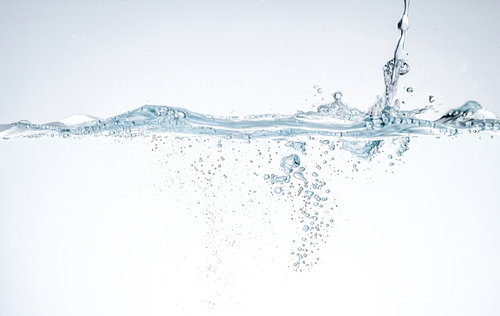 水槽の水面に注がれる透明な水の流れと気泡