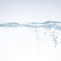 ミネラルウォーターの水面に浮かぶ気泡のの写真