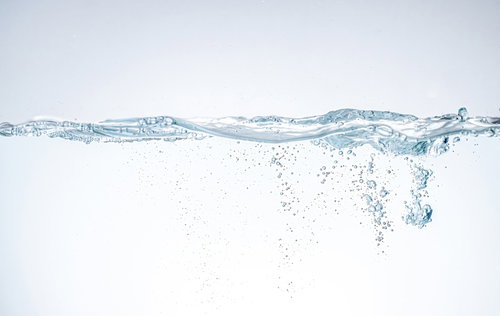 ミネラルウォーターの水面に浮かぶ気泡の