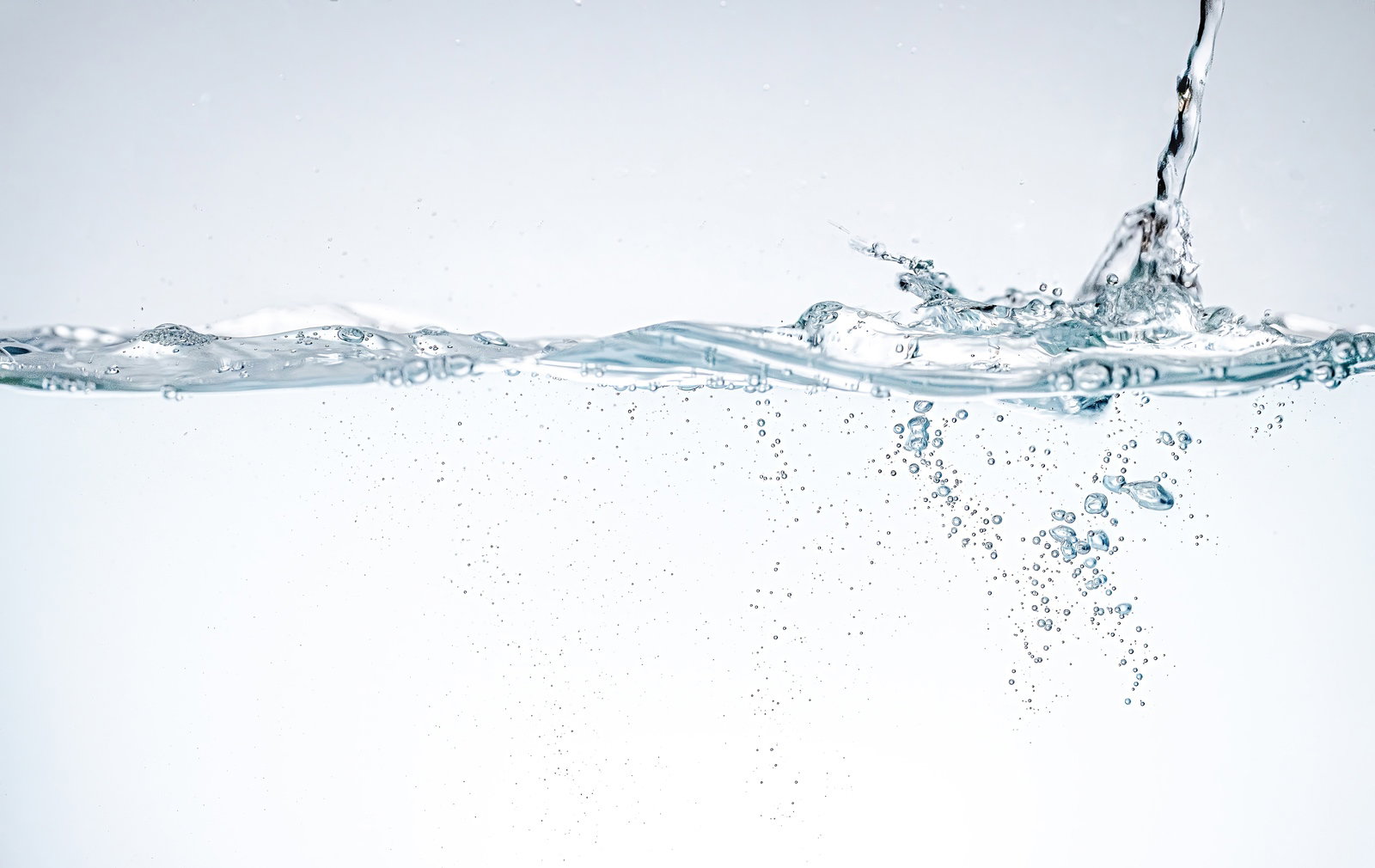 勢いよく水が注がれ、白い泡と気泡が立つ透明な水面