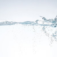 透明な水槽に勢いよく注がれる水面と気泡の流れの写真