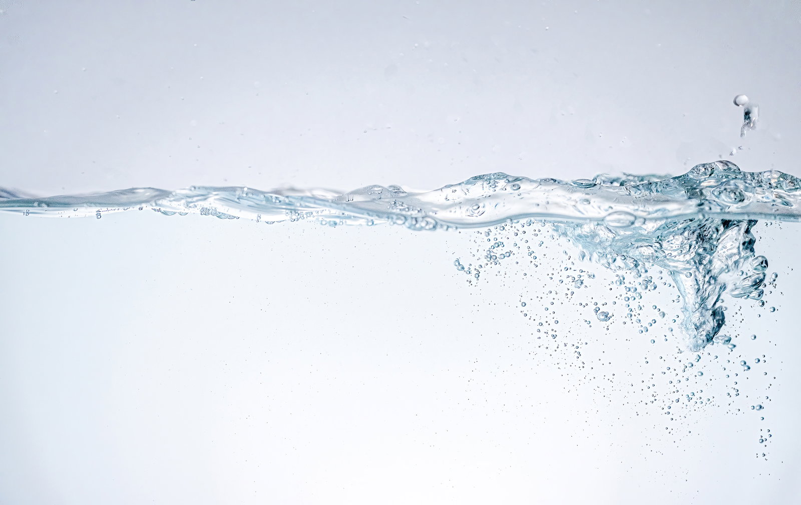 水が注がれて波立ち、気泡が浮遊する透明な水槽