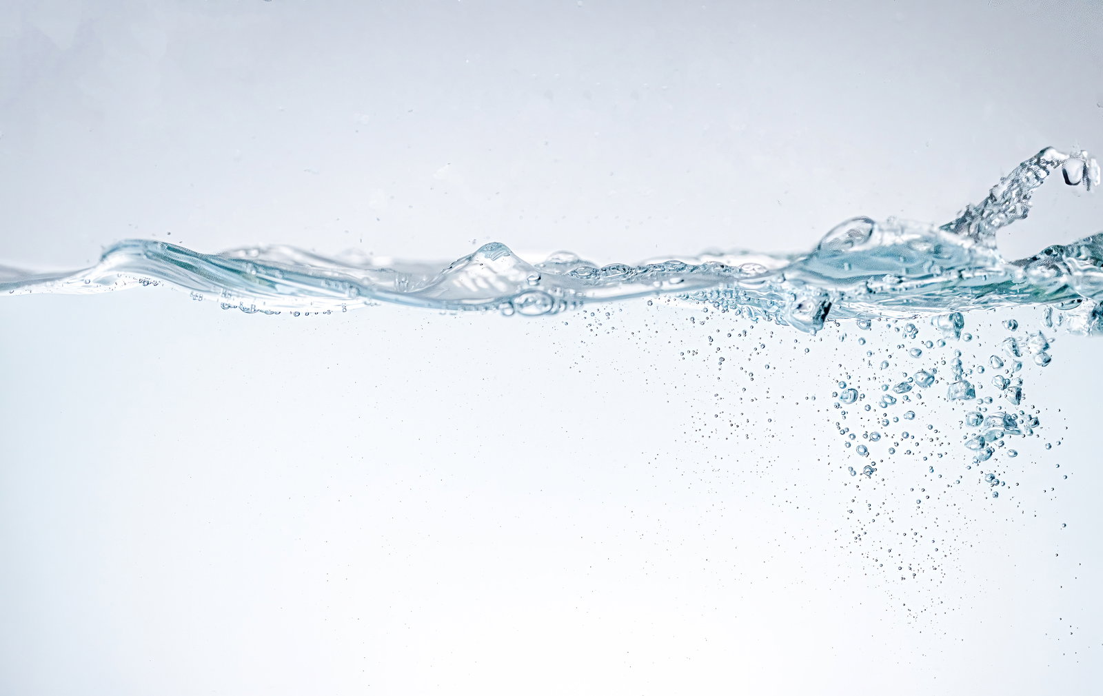 水槽内で気泡が立ち上り、水面に波が広がる透明な液体の様子