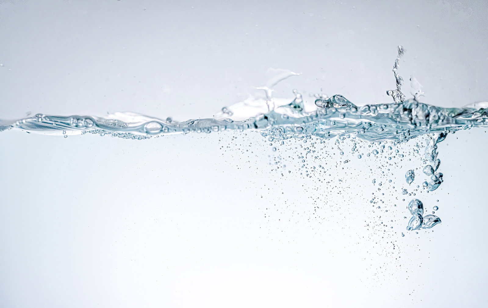 水槽内で波立つ水面に無数の気泡が上昇している