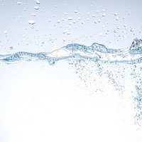 透明な水面から立ち上がる波紋と無数の気泡の写真