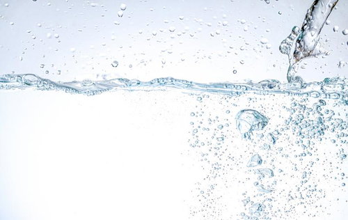 透明な水面に落ちる水滴と立ち上がる気泡