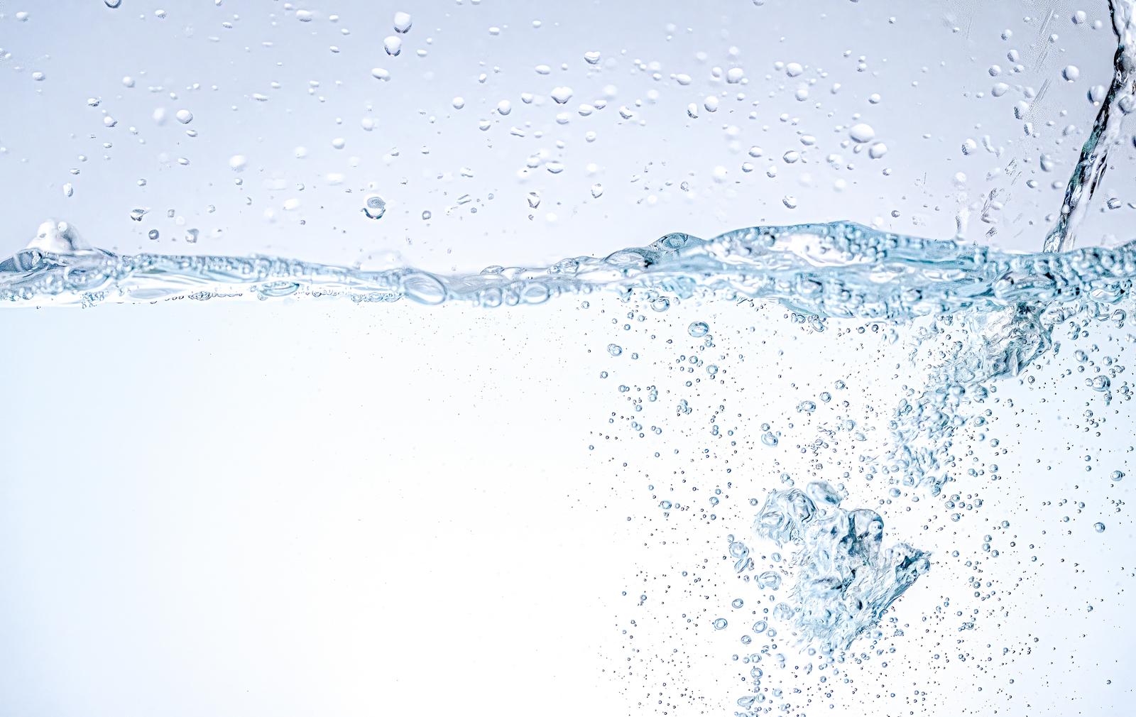 Countless bubbles rising and water splashes flowing in from the right in transparent water