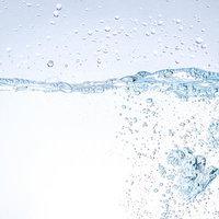 クリアな水中に舞い上がる無数の気泡と動的な水しぶきの写真