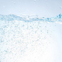 クリアなミネラルウォーターの中に踊る細かな気泡と水面の写真