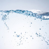 水槽をかき混ぜて立ち上る気泡と水しぶきのシズルの写真