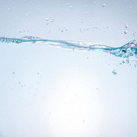 透明な水の波紋ときらめく気泡が浮かぶ清涼感のある水面の写真