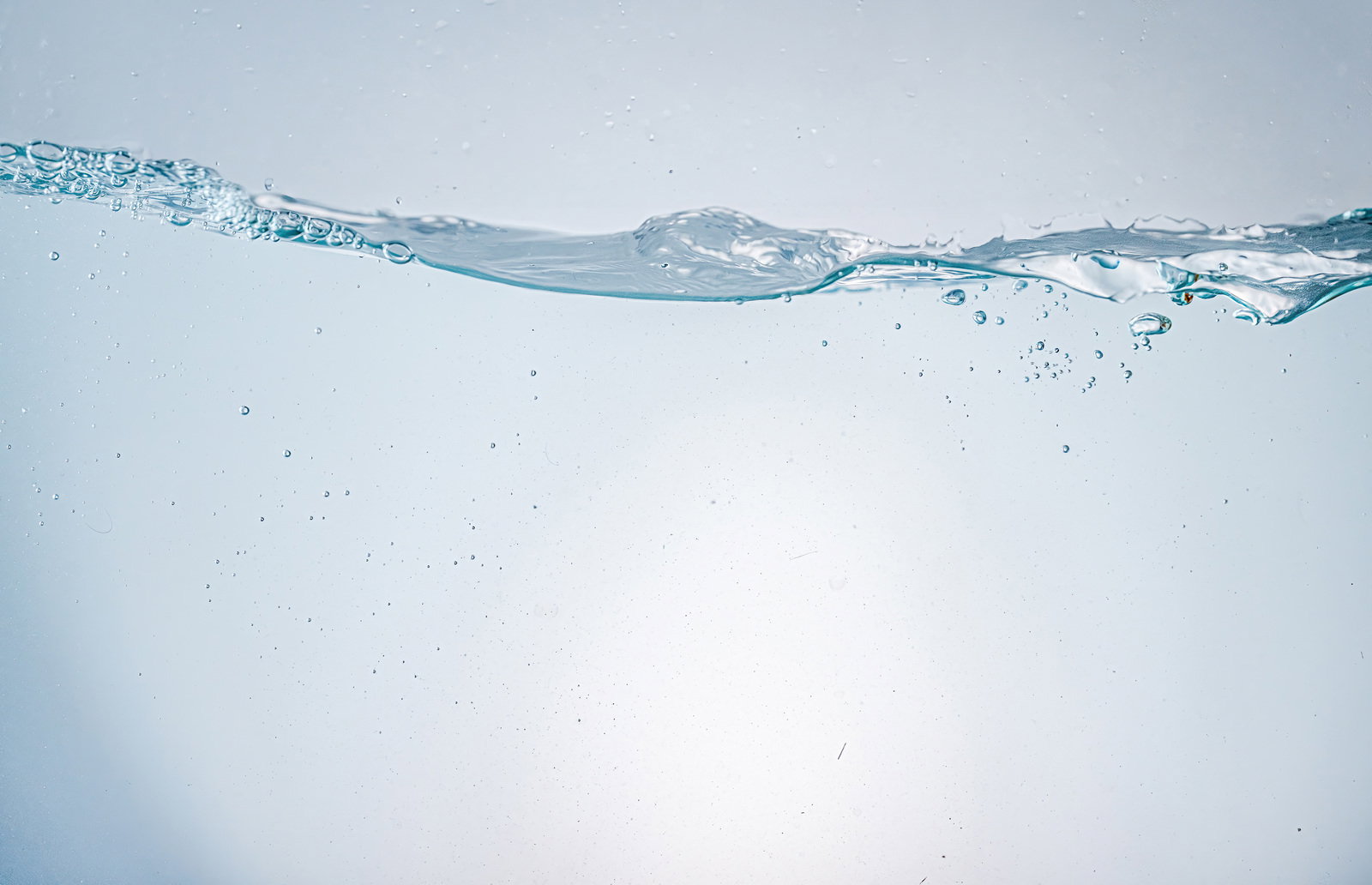 透明な水中に浮遊する気泡と水面の写真