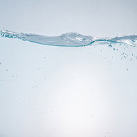 気泡が少ない穏やかな水面と水中の気泡が浮遊する透明な液体の写真
