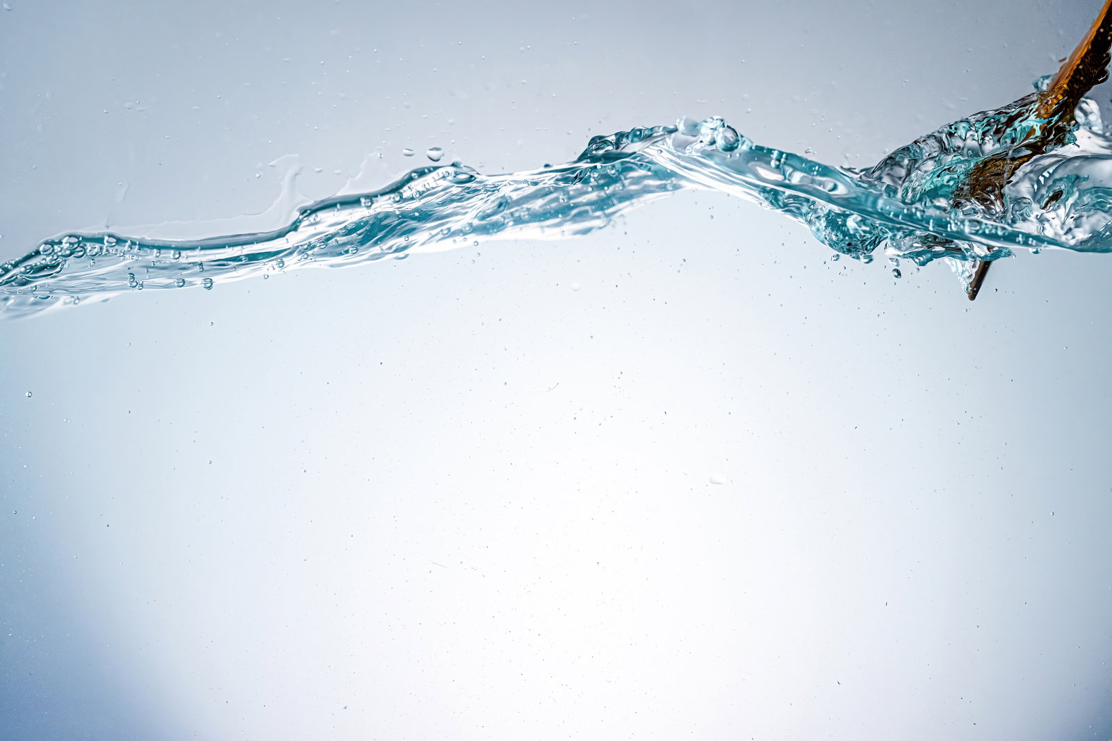 竹製のひしゃくから水槽に注がれた透明な水と気泡