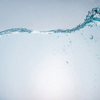 水槽に大きな波を起こす水しぶきと気泡の流動の写真