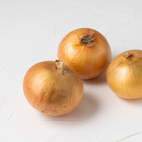 白い背景に転がる三個の玉葱の写真