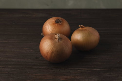 暗がりの木目に転がる玉葱 - 茶色い外皮の食材