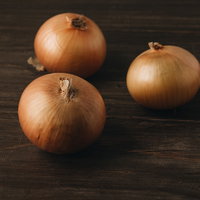木目調の机に並べられた茶色い玉葱の食材写真の写真