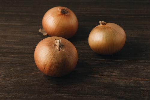 木目調の机に並べられた茶色い玉葱の食材写真