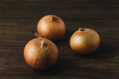 木のテーブルに無造作に置かれた3個の玉葱