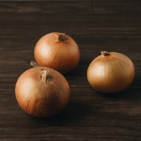 木製机に置かれた3個の玉葱と影の食材の写真