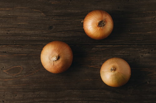 木製テーブルに微妙な距離感で並ぶ三個の玉葱