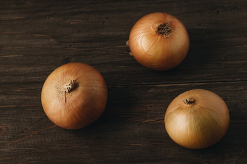 距離をとって保管された玉葱、木製テーブルに三角形状に配置