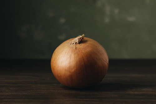 木目のテーブルの上に寂しそうに佇む玉葱