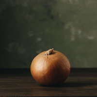 木製テーブルに置かれた玉葱の表面に残る光と影の写真