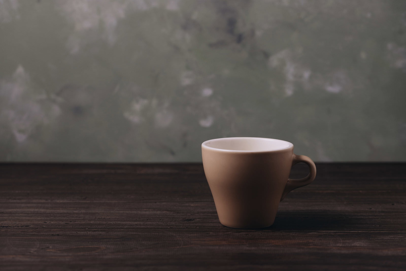 木製テーブルの上に置かれたベージュ色のマグカップ