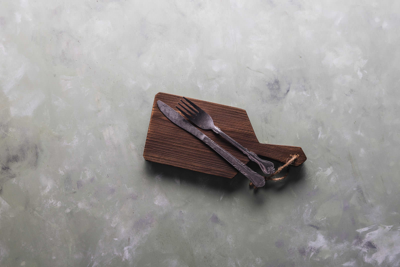 木製のカッティングボードの上に置かれた古色のナイフとフォーク